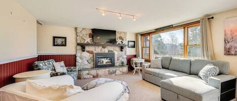 A cozy living room with a stone fireplace, a sofa, a loveseat, and a coffee table.