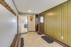 Un pasillo con un banco de madera, un reloj y una puerta con ventanal.
