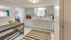 A kitchen with white cabinets, a wooden dining table, and a patterned rug. - Near Skiing & Snowmobiling: Home in Mars Hill! (Mars Hill)