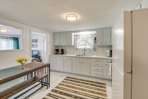 Una cocina con armarios blancos, una mesa de comedor de madera y una alfombra estampada.