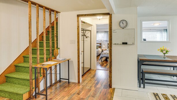 A staircase with green carpeted steps and wooden handrails, leading to a room with a wooden floor and a table with a vase of flowers. - Near Skiing & Snowmobiling: Home in Mars Hill! (Mars Hill)