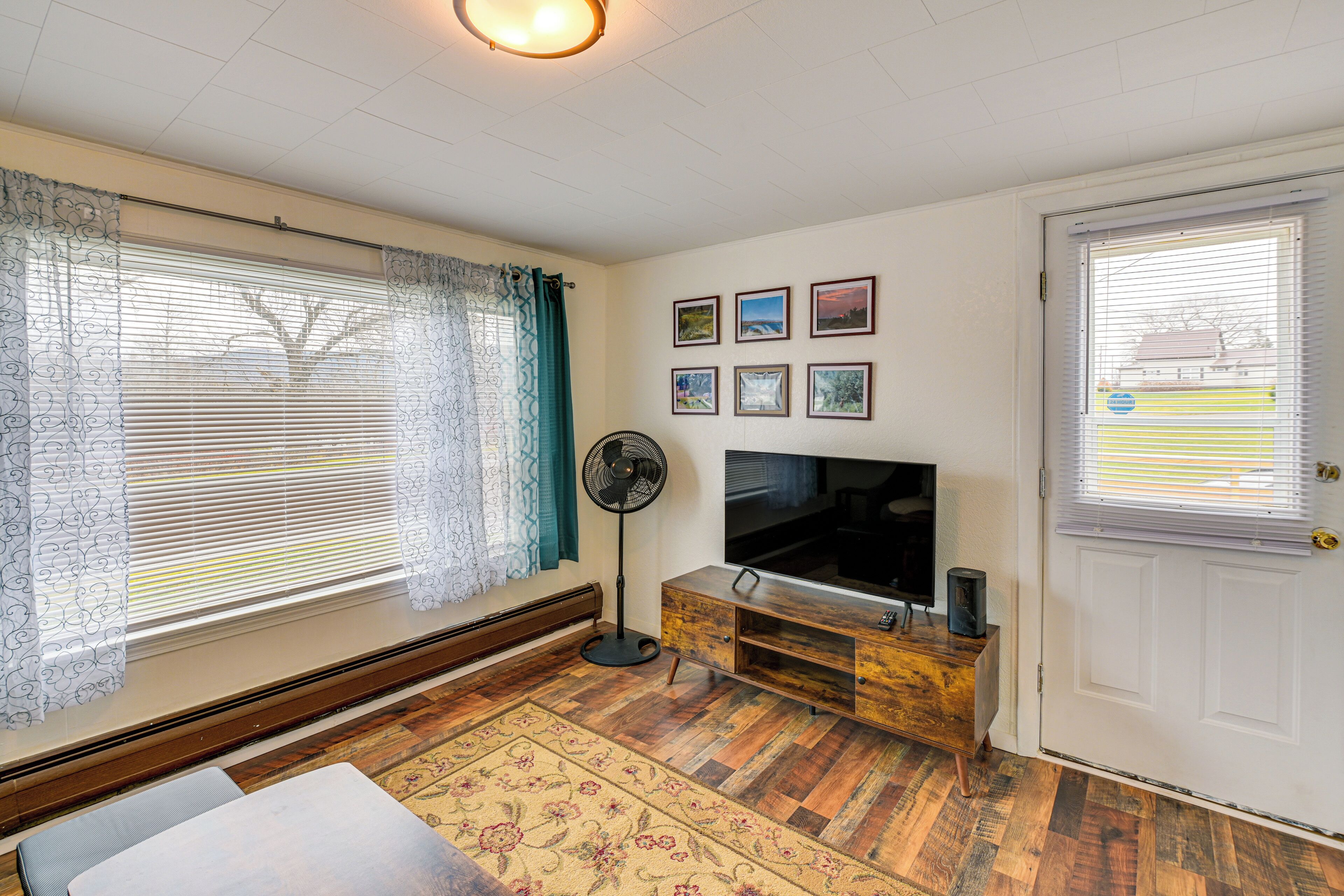 Una sala de estar con televisor, mueble de madera y una puerta.