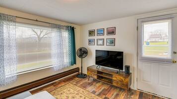 Una sala de estar con televisor, mueble de madera y una puerta.