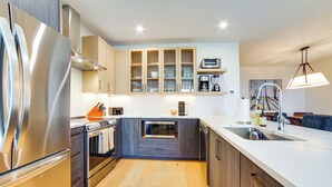 A modern kitchen with stainless steel appliances, wooden cabinets, and a central island. - Ski-in/out Townhome w/ Views at Okemo Resort! (Ludlow)
