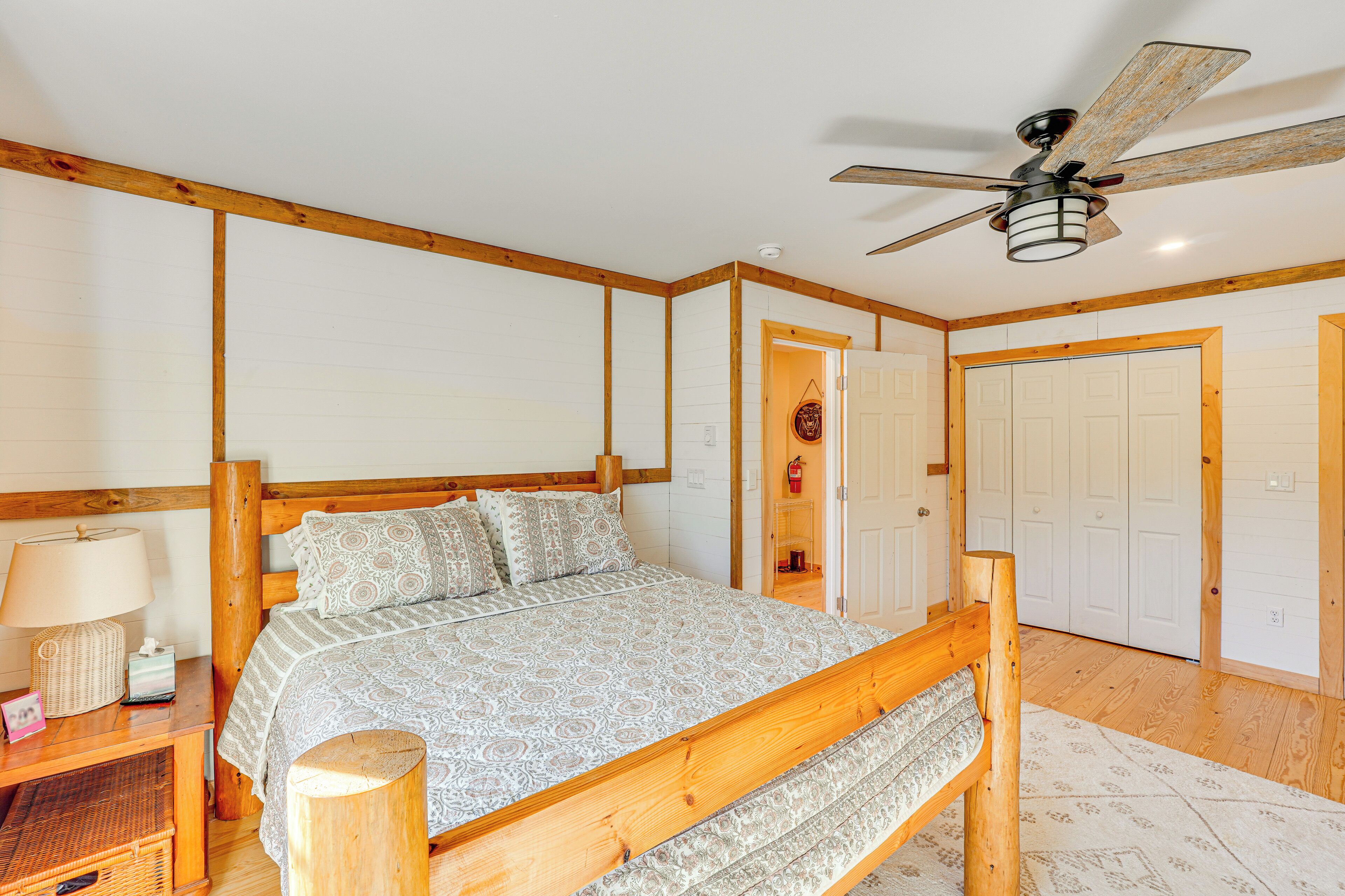 A bedroom with a wooden bed, a ceiling fan, and white walls.