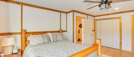 Un dormitorio con cama de madera, ventilador de techo y paredes blancas.