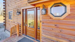 A wooden cabin with a wooden staircase leading to a door, a window with a decorative glass design, and a lantern on the wall. - Cabin 4 Mi to Belleayre Mountain: Ski, Hike & Fish (Fleischmanns)