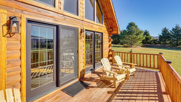 A wooden cabin with large sliding glass doors, a deck with chairs, and a view of a grassy area. - Cabin 4 Mi to Belleayre Mountain: Ski, Hike & Fish (Fleischmanns)