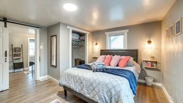 Un dormitorio con cama, mesitas de noche, un armario y una ventana.