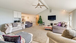 A spacious living room with a high ceiling, a ceiling fan, a flat-screen TV mounted on the wall, and a Christmas tree. - Water Views & Decks: Spacious La Grange Retreat (La Grange)