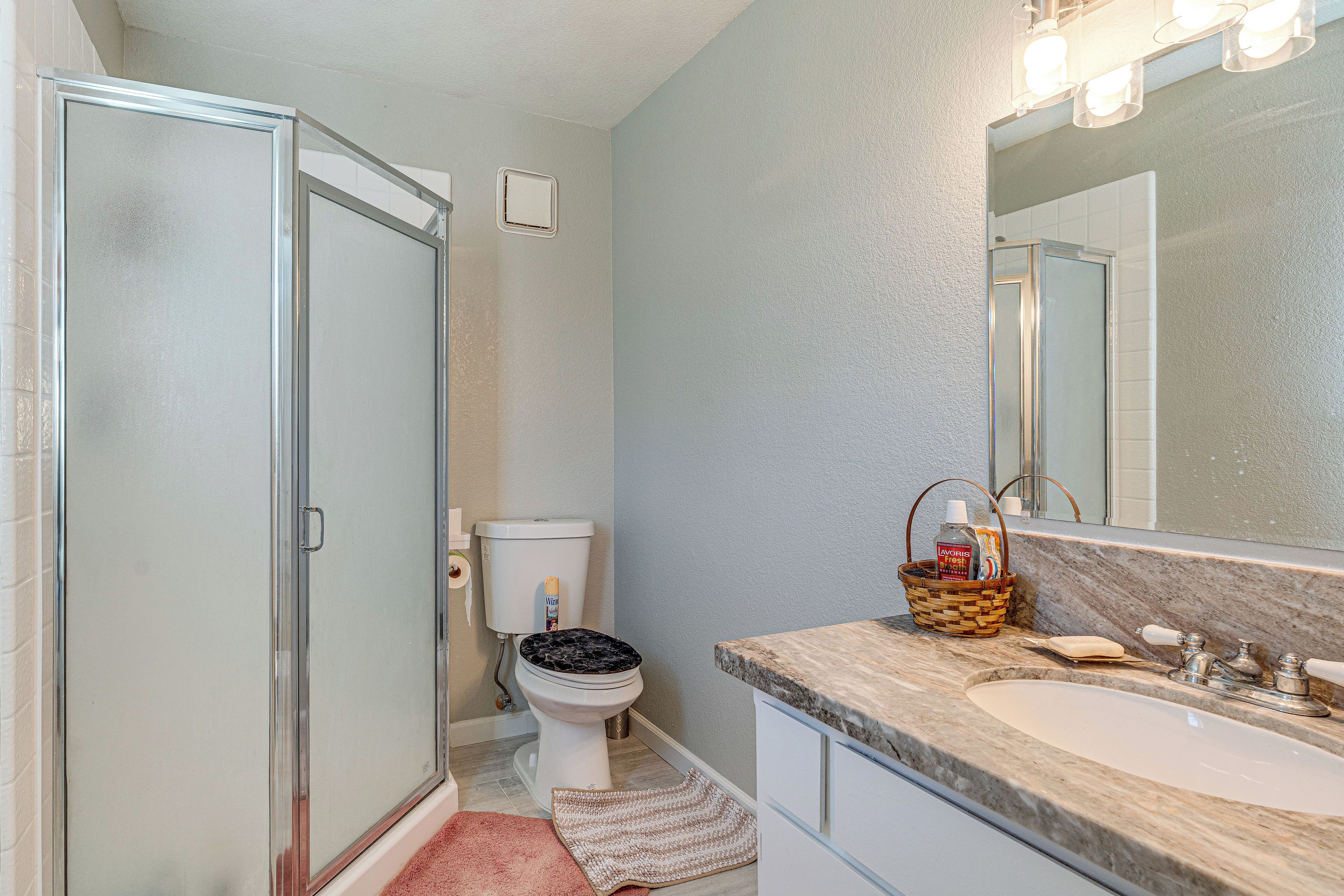 Ein Badezimmer mit Dusche, Toilette, Waschbecken und Spiegel.