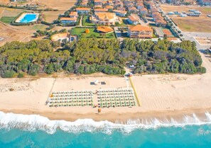 Pantai pribadi, pasir putih, kursi berjemur, dan payung pantai