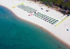 Privat strand, hvit sand, solsenger og parasoller