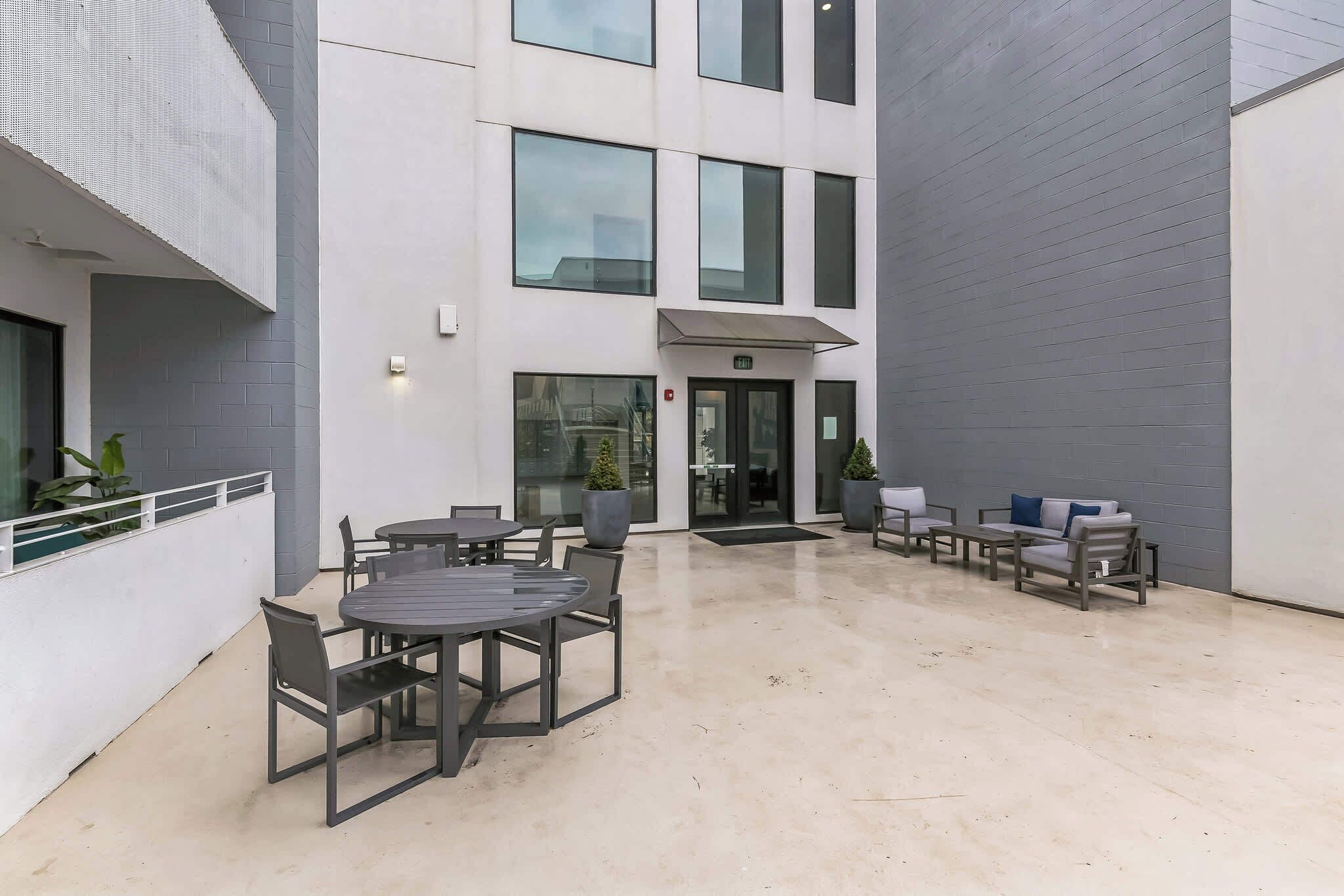 A modern outdoor patio area with a seating arrangement and a building entrance.