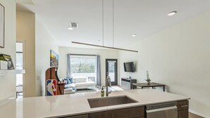 A modern kitchen with a central island, built-in appliances, and a dining area with a sofa and table.