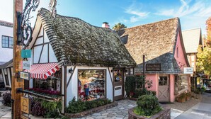 A traditional building with a thatched roof and a shop front displaying various items.