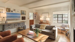 A spacious living room with a large painting, a wooden cabinet, a sofa, a coffee table, and a fireplace.