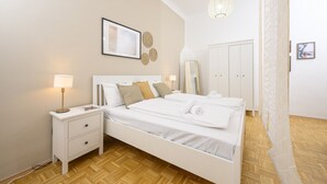 Une chambre à coucher comprenant un lit, des tables de chevet, une armoire et un luminaire suspendu.