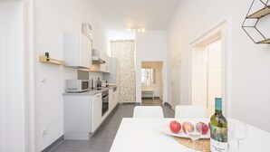 Une cuisine moderne avec des meubles blancs, un four à micro-ondes et un coin repas avec une table dressée pour deux personnes.