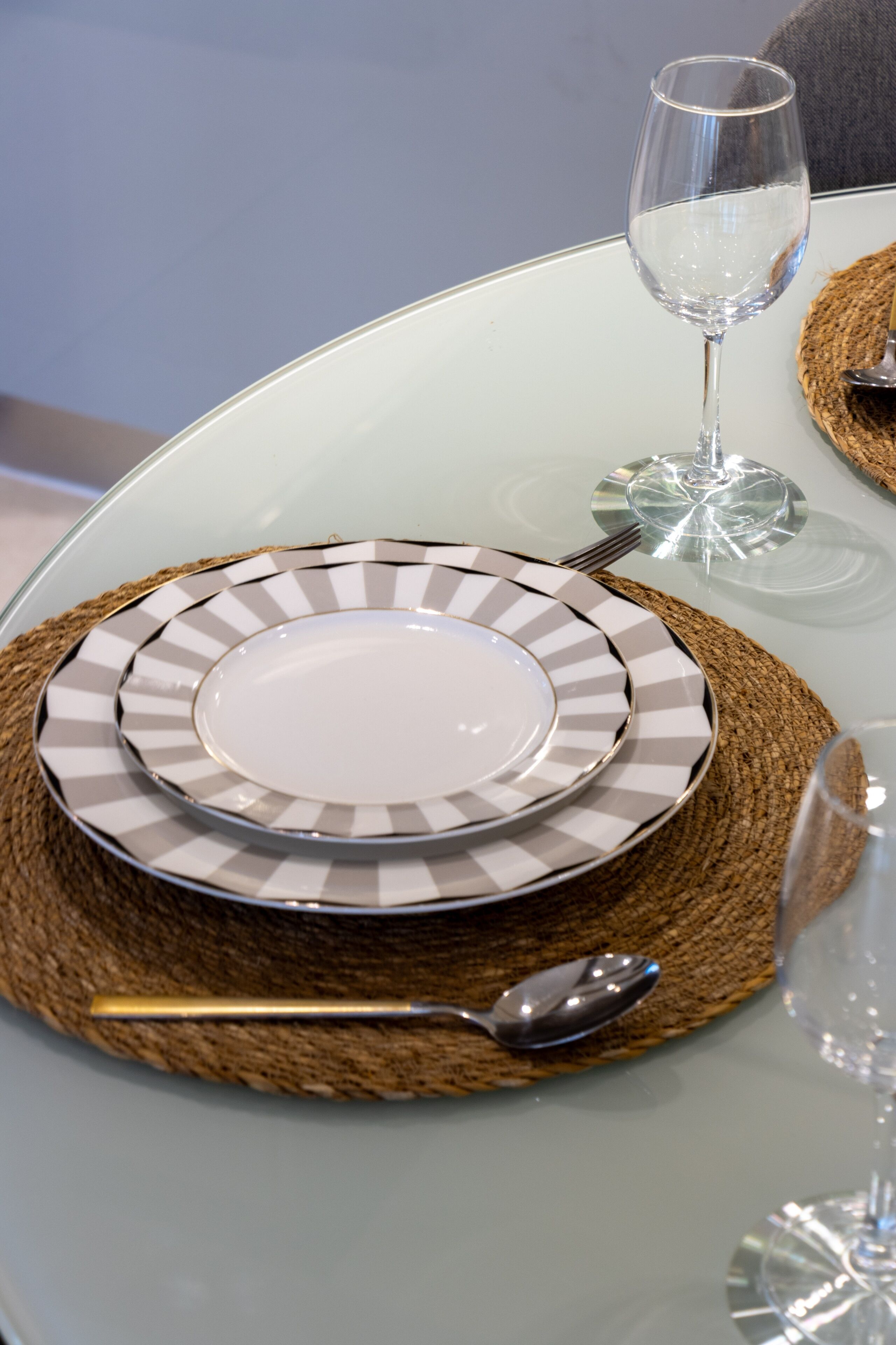 Una mesa servida con platos, una cuchara y una copa.