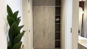 A hallway with a large plant, a wooden bench, a patterned rug, and a closet with shelves. - Kease Narjis A-12 Luxury Gold AX18 (Riyadh)