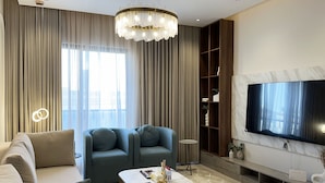 A modern living room with a sofa, two armchairs, a coffee table, a TV, and a bookshelf. - Kease Narjis A-12 Luxury Gold AX18 (Riyadh)