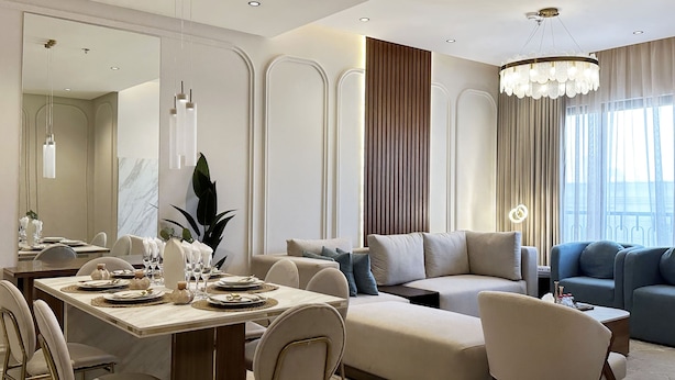 A modern dining area with a large table set for six, a sofa, and a blue couch. - Kease Narjis A-12 Luxury Gold AX18 (Riyadh)