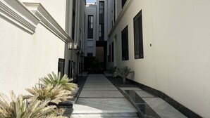 A narrow, white-walled corridor with a tiled floor, leading to a building entrance. - Kease Narjis A-12 Luxury Gold AX18 (Riyadh)