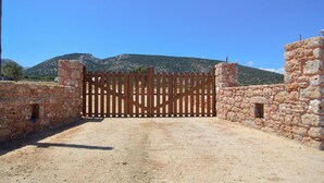 A stone gate with a wooden fence, leading to a mountainous landscape. - Villa Rouvis With Outdoor Hot Tub (Naxos)