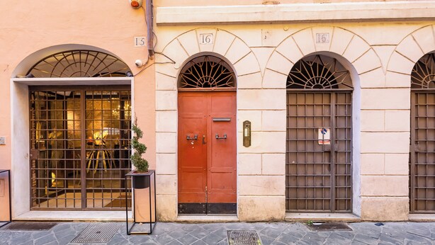 A building facade with three numbered doors, a metal gate, and a potted plant. - Spanish Steps Spacious Apartment (Rome)
