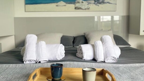 Una cama bien hecha con dos almohadas y un par de toallas enrolladas sobre la cama.