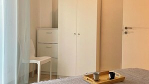 Un dormitorio con cama, armario, escritorio y silla.