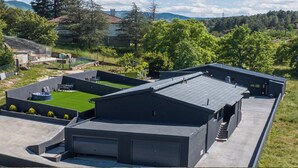 Un bâtiment moderne doté d’un toit plat, d’une pelouse verdoyante et d’une petite piscine.