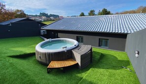 Une maison moderne dotée d’une piscine, d’un jacuzzi et d’une pelouse bien entretenue.