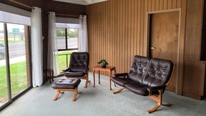 Een kamer met twee leren stoelen, een bijzettafeltje en een plafondventilator.