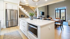 A modern kitchen with a large island, stainless steel appliances, and a staircase leading to a dining area.