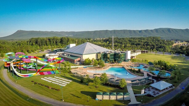 A resort with a water park, a swimming pool, and a large building with a sloped roof.