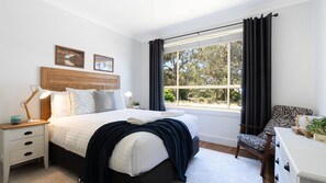 Cozy retreat with a large bed, nightstand, dresser, and comfortable chair.