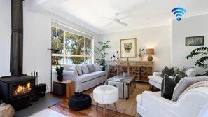 A living room with a fireplace, white sofas, a coffee table, and a large window with a view.