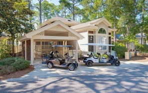 Ein Wohnhaus mit überdachter Garage, zwei Golfcarts und einem gepflegten Rasen.