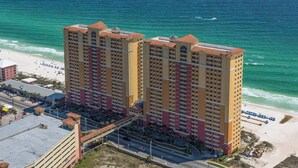 Un hôtel de grande hauteur doté de nombreux balcons, offrant une vue sur la plage et disposant d’un parking.