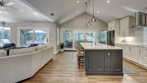 A modern kitchen with a large island, dark cabinetry, and pendant lighting.