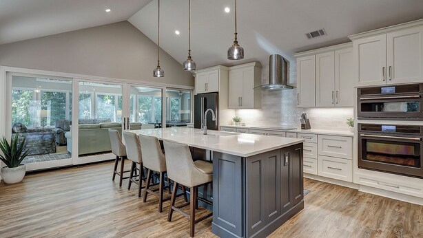 A modern kitchen with a large island, stainless steel appliances, and a view to the outdoors.