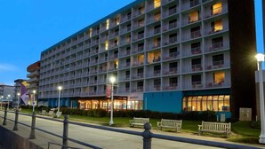 A multi-story hotel with balconies, a visible restaurant, and a well-lit exterior. - Boardwalk Below, Beach Ahead (Virginia Beach)