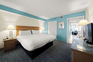A hotel room with a bed, bedside lamps, a TV, a desk, and a wardrobe. - Sun, Sand & a Rainy Day Backup (Virginia Beach)
