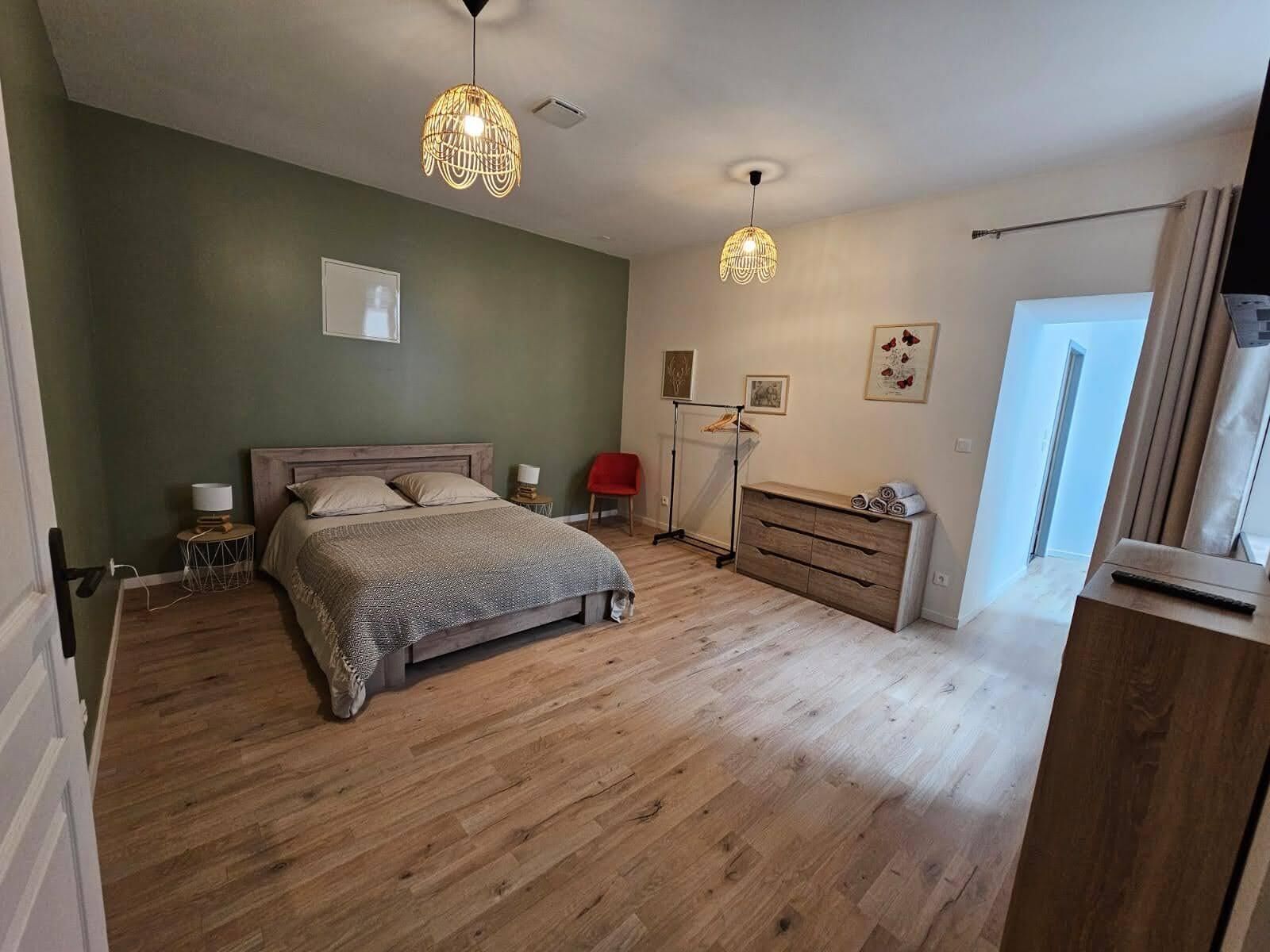 Una camera da letto con un letto in legno, comodini, una cassettiera e una lampada a sospensione.