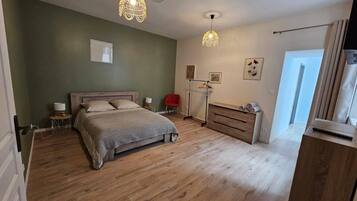 Una camera da letto con un letto in legno, comodini, una cassettiera e una lampada a sospensione.