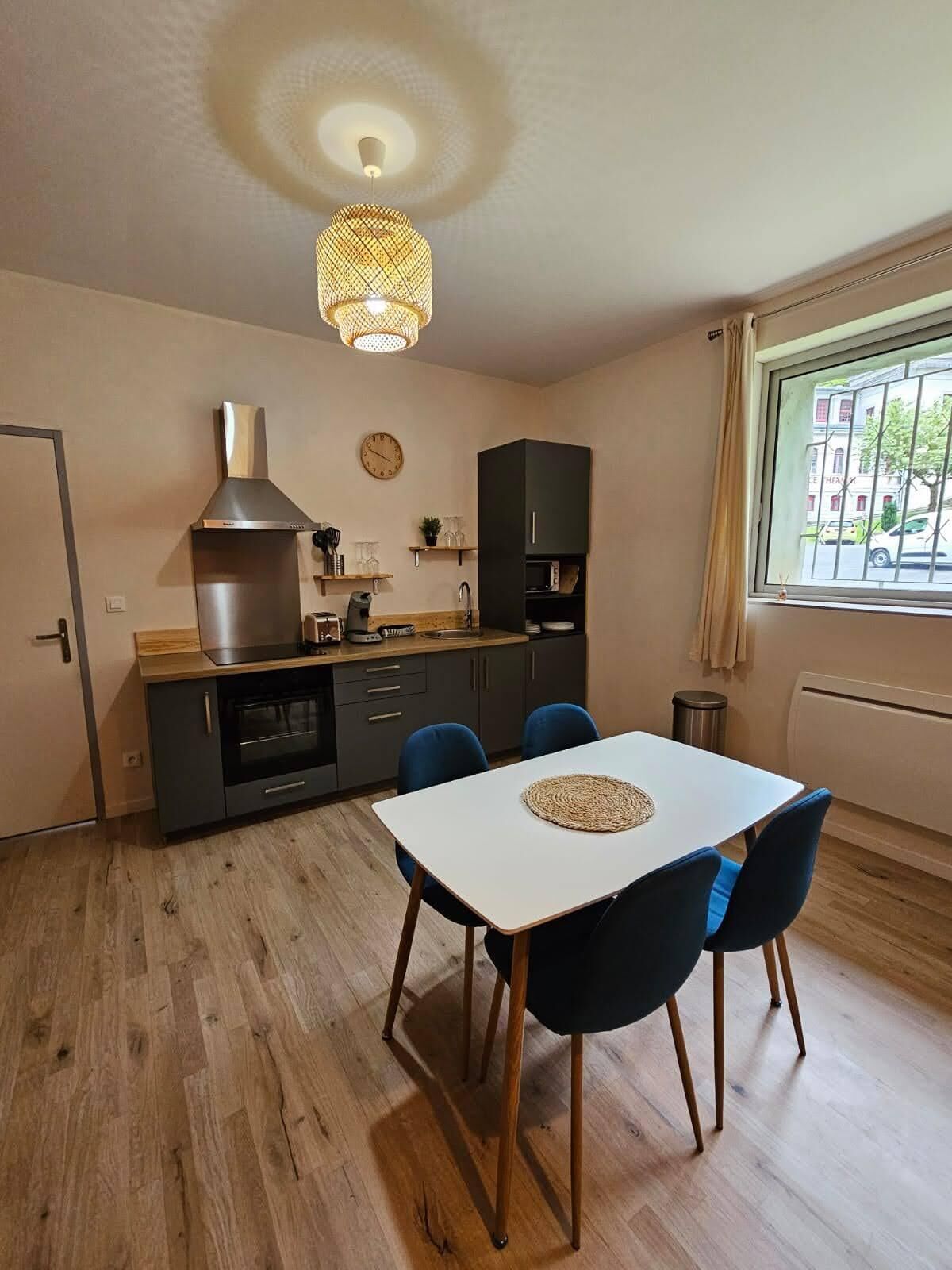 Cocina compacta con estufa moderna, un lavamanos y un comedor con mesa y sillas.