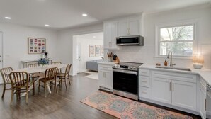 Una cocina moderna con muebles blancos, estufa de acero inoxidable y microondas.