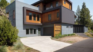 Et moderne hus i to etager med garage, store vinduer og facade i en blanding af træ og metal.